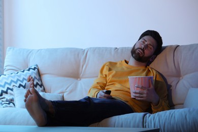 Photo of Man sleeping while watching TV with popcorn on sofa