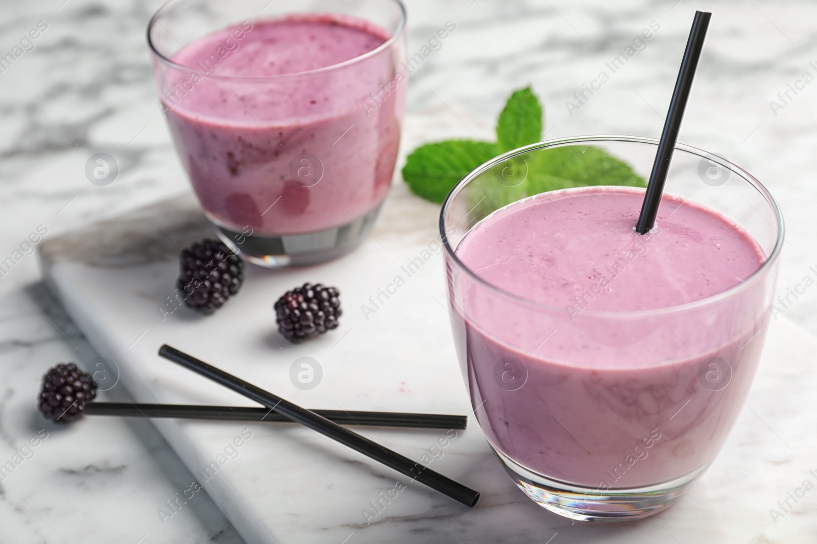 Photo of Glasses with tasty blackberry yogurt smoothies on table