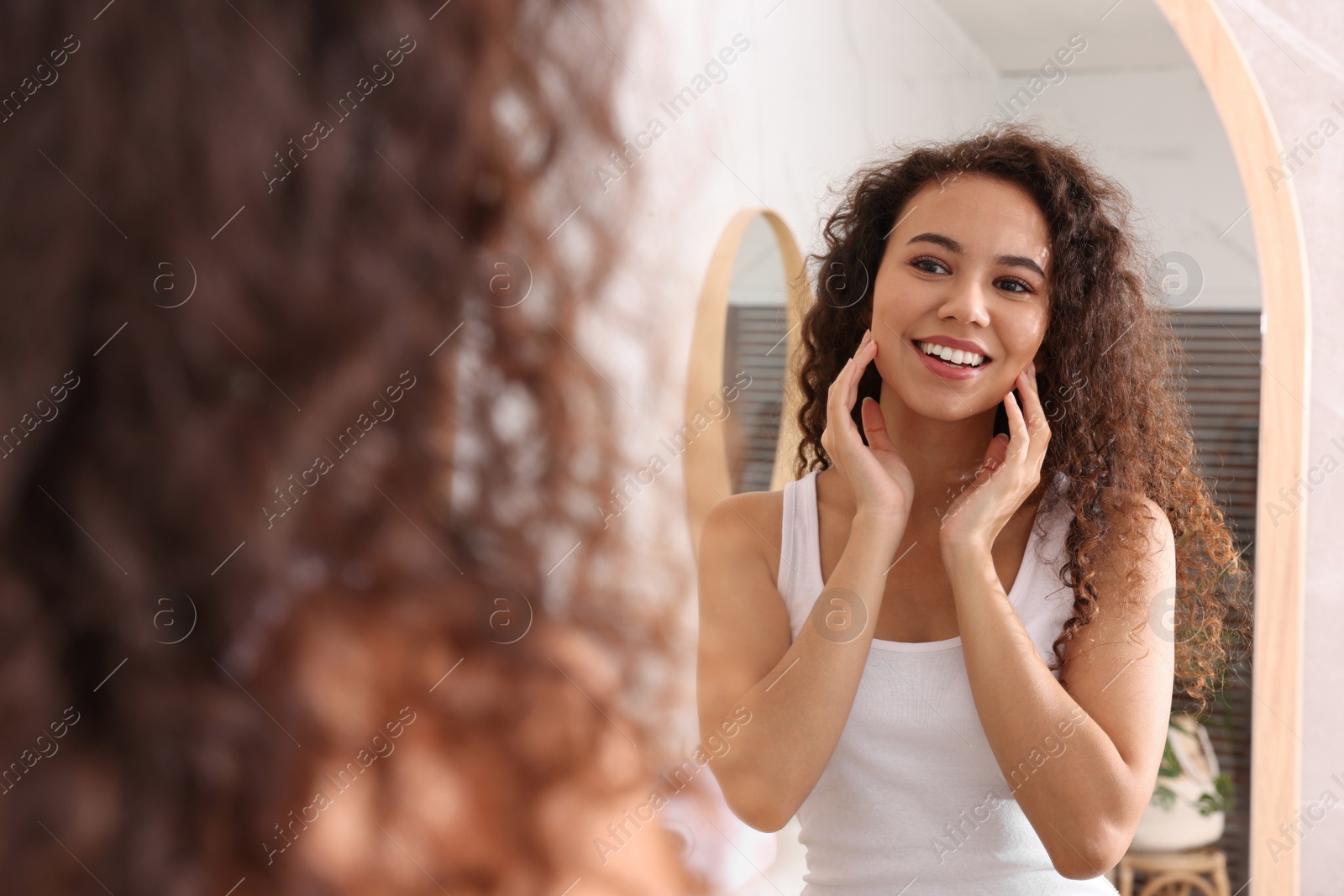 Photo of Beautiful African American woman near mirror in bathroom