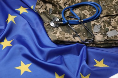 Photo of Stethoscope and military uniform on flag of European Union, closeup