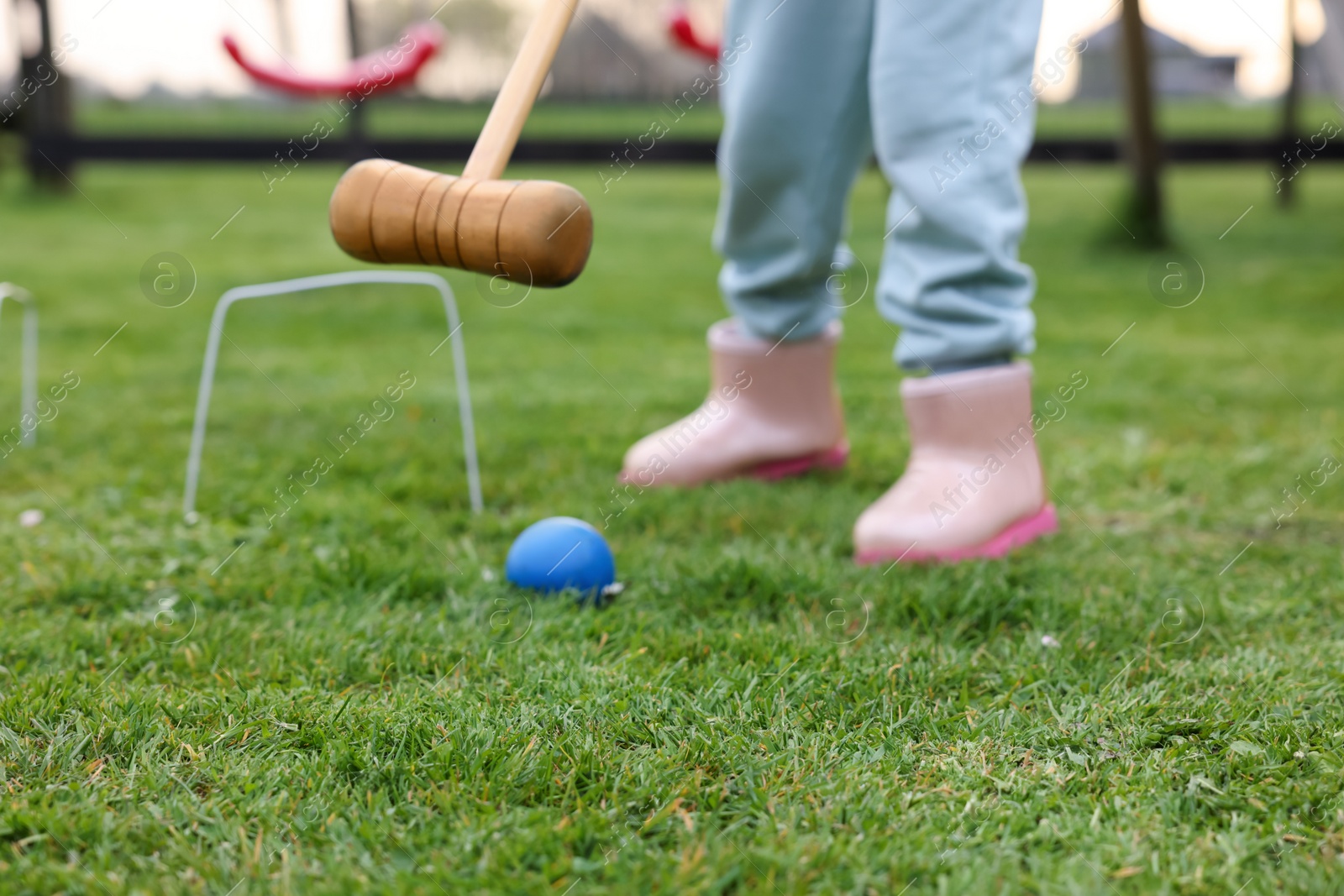 Photo of Girl playing croquet on green grass outdoors, closeup