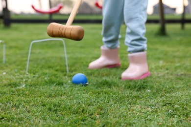 Girl playing croquet on green grass outdoors, closeup