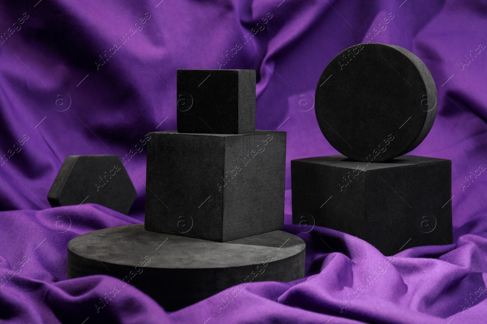 Photo of Black geometric figures on purple fabric. Stylish presentation for product