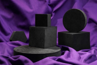 Photo of Black geometric figures on purple fabric. Stylish presentation for product