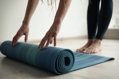 Young woman with yoga mat indoors, closeup