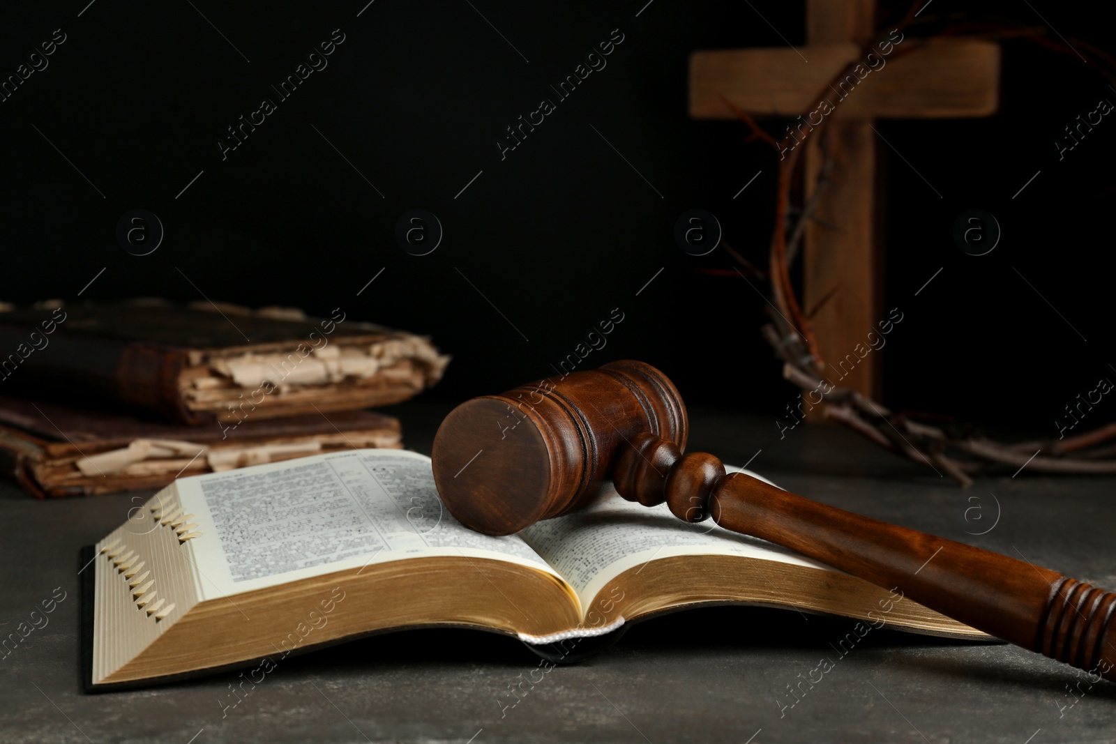 Photo of Judge gavel, bible, wooden cross and crown of thorns on grey table