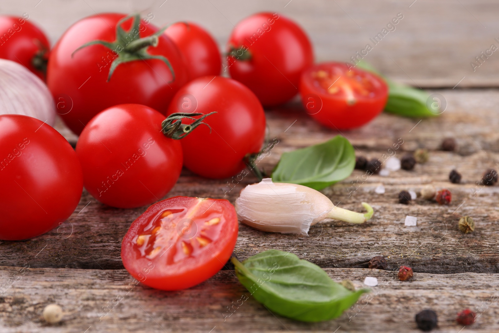 Photo of Ripe tomatoes, basil, garlic and spices on wooden table, closeup