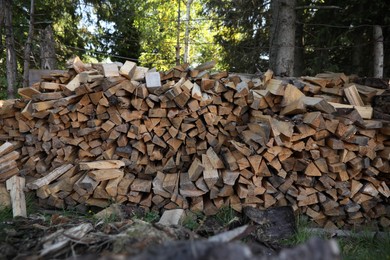 Stack of cut firewood on green grass outdoors. Heating in winter