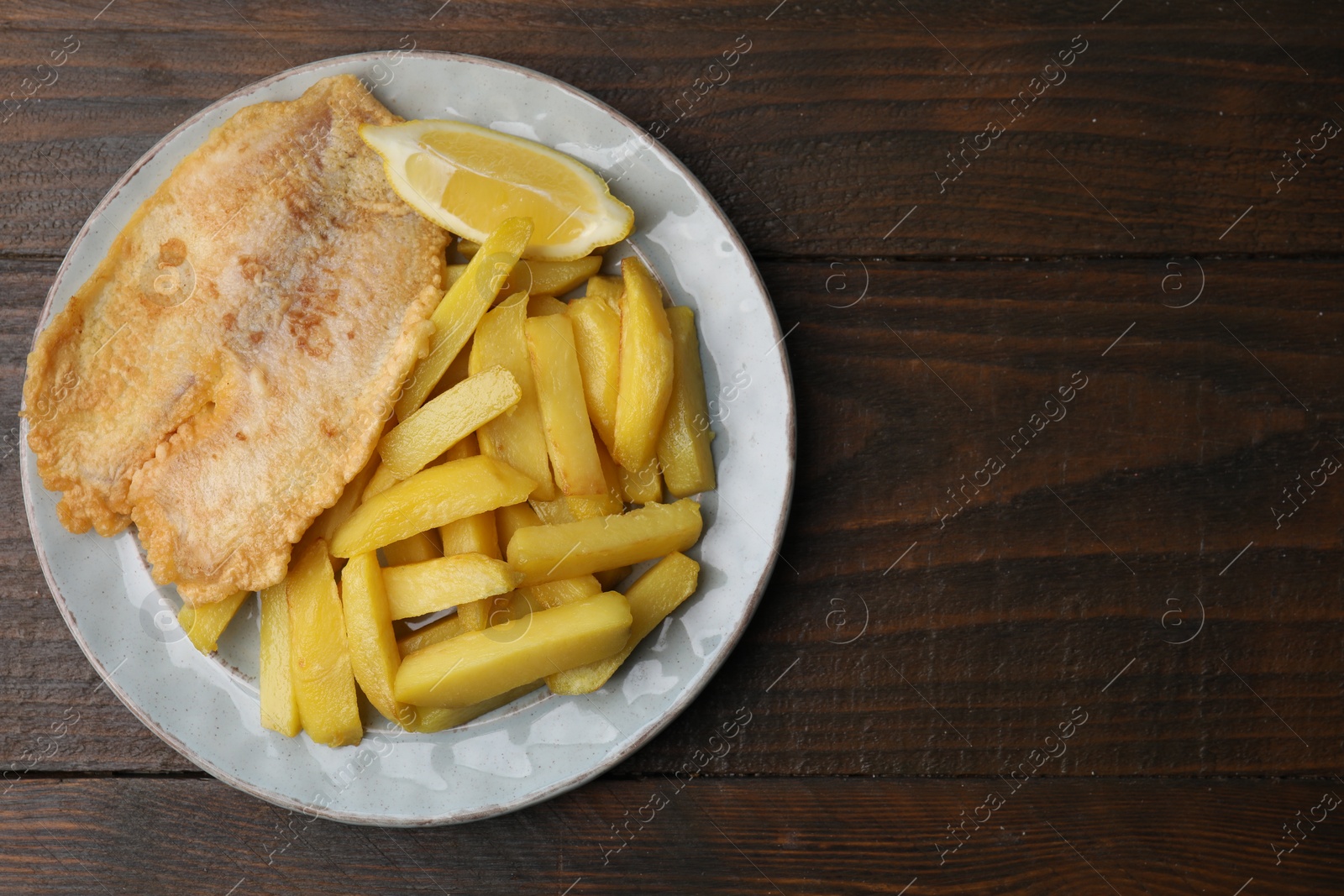 Photo of Delicious fish and chips on wooden table, top view. Space for text