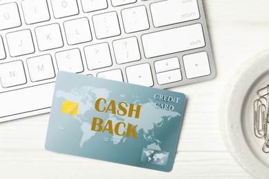 Image of Cashback credit card near computer keyboard on white table, flat lay