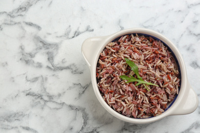 Photo of Tasty brown rice on marble table, top view. Space for text