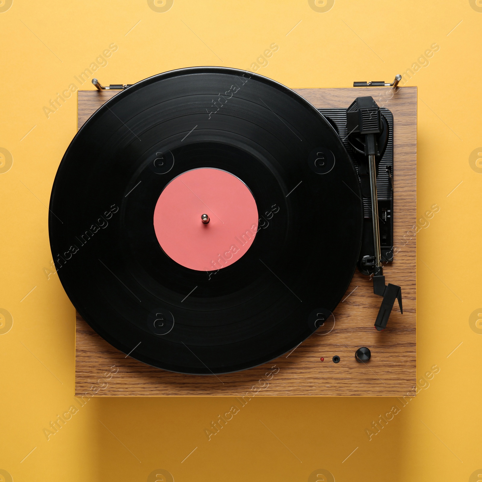Photo of Modern turntable with vinyl record on orange background, top view
