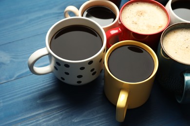Photo of Many cups of different coffee drinks on blue wooden table