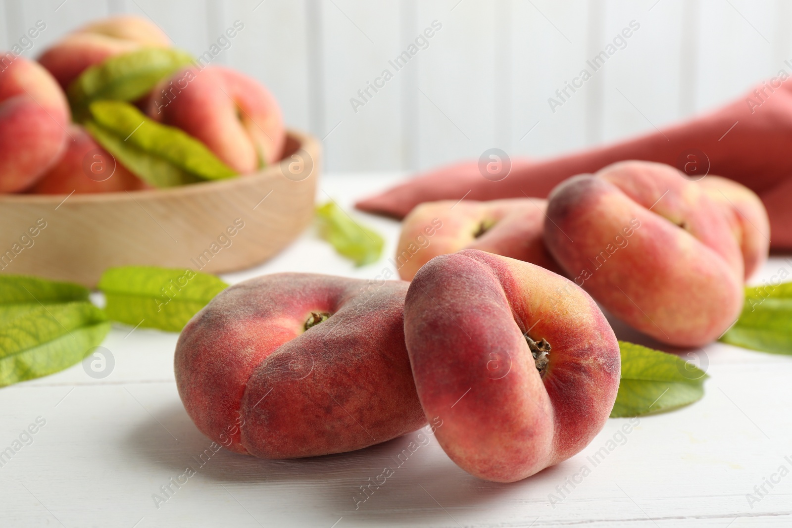 Photo of Fresh ripe donut peaches on white wooden table, closeup