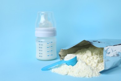 Photo of Bag of powdered infant formula, feeding bottle and scoop on light blue background, space for text. Baby milk