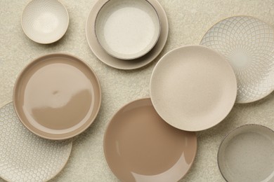 Beautiful ceramic plates and bowls on beige table, flat lay