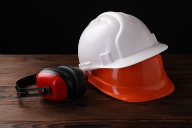 Photo of Safety equipment. Hard hats and protective headphones on wooden table