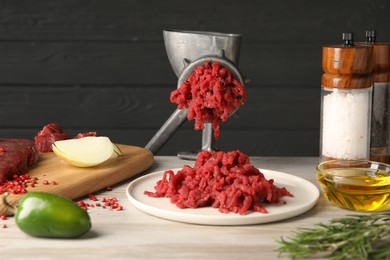 Photo of Metal meat grinder with minced beef and products on light wooden table