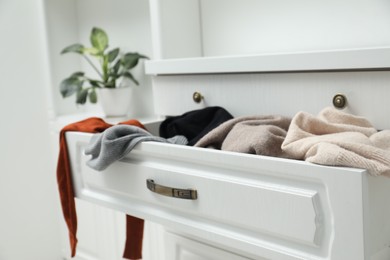 Cluttered chest of drawers indoors, closeup. Clothes in mess