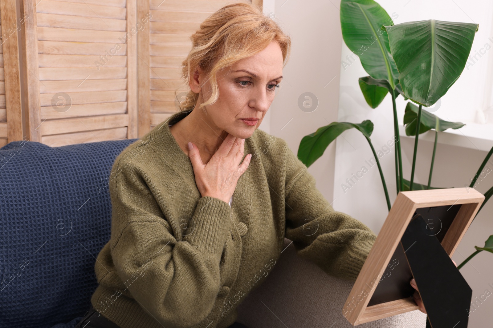 Photo of Upset middle aged woman with photo frame at home. Loneliness concept