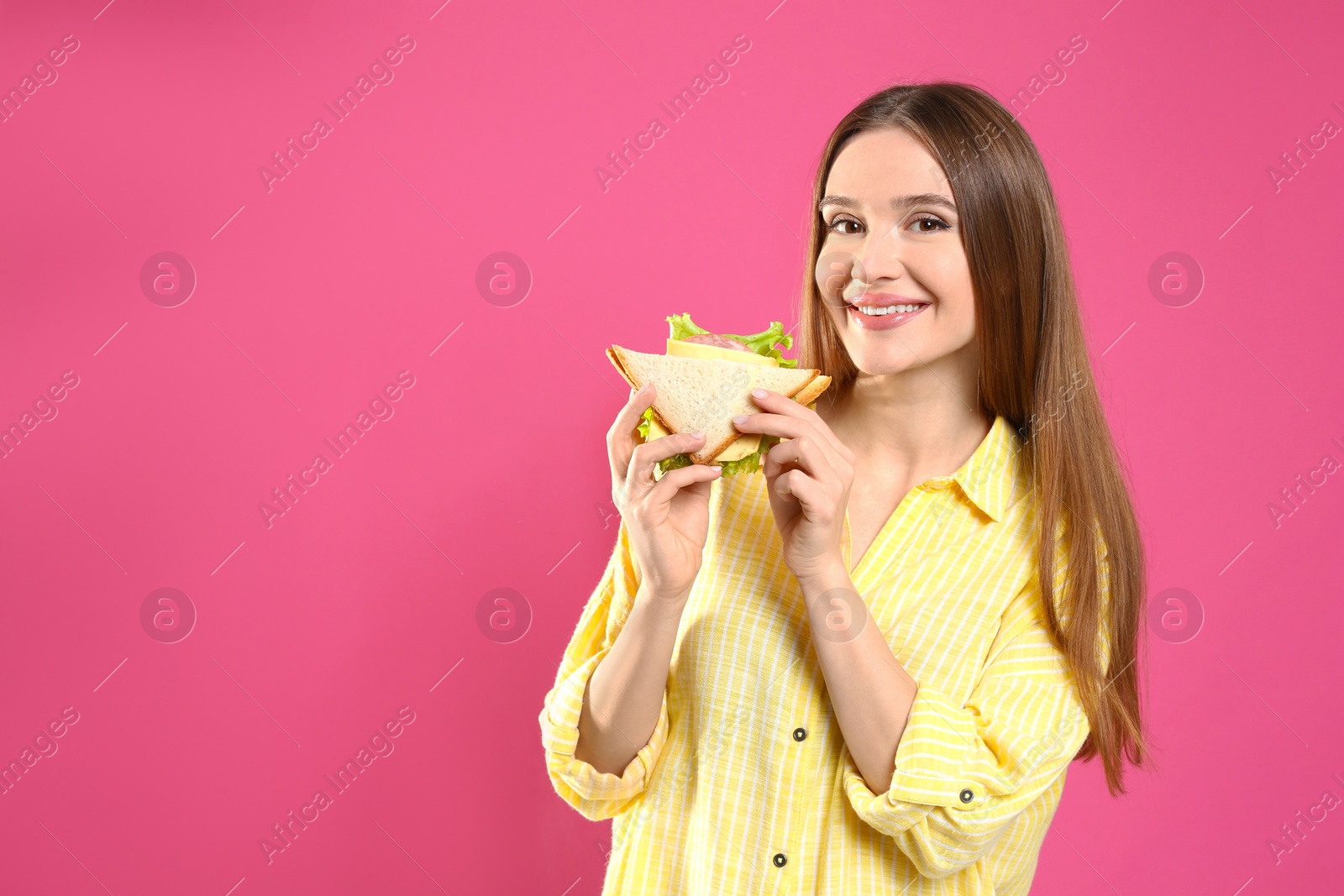 Photo of Young woman with tasty sandwich on pink background