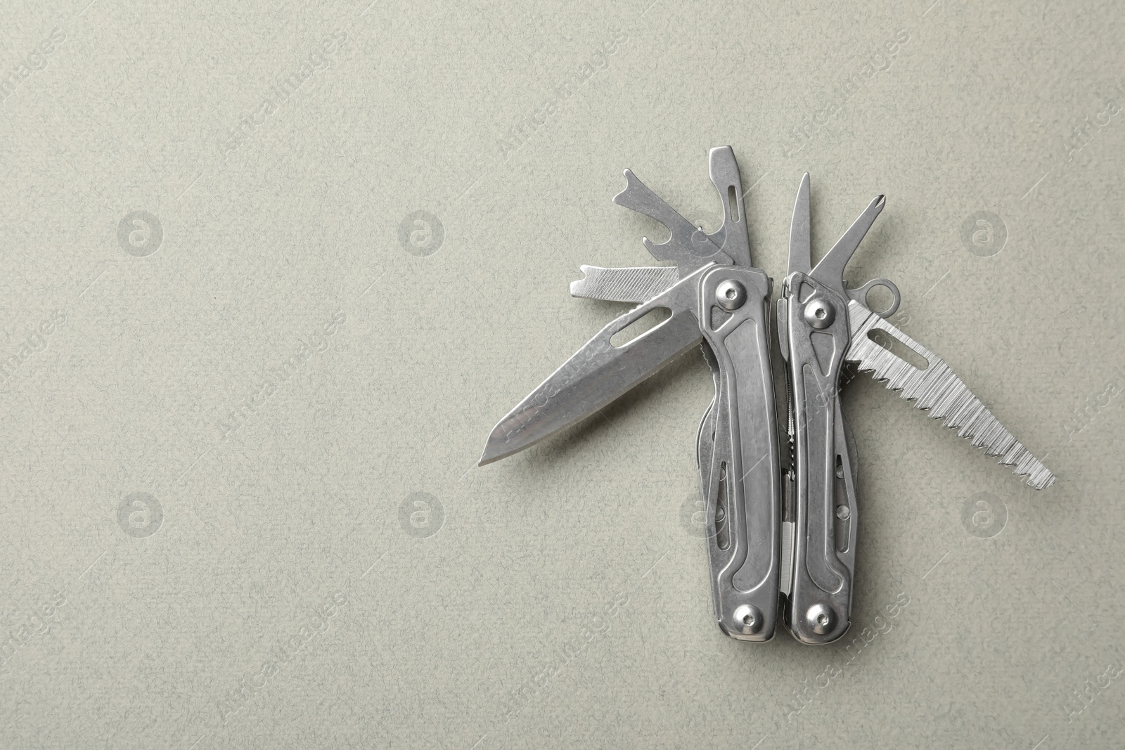 Photo of Compact portable metallic multitool on light grey background, top view. Space for text