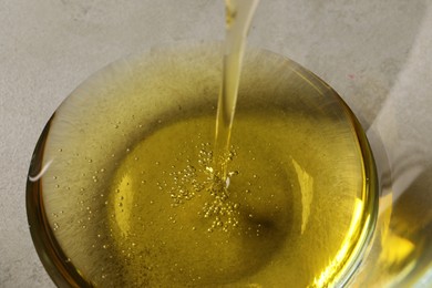 Photo of Pouring cooking oil into glass bowl, closeup