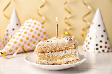 Slice of delicious birthday cake with candle on table