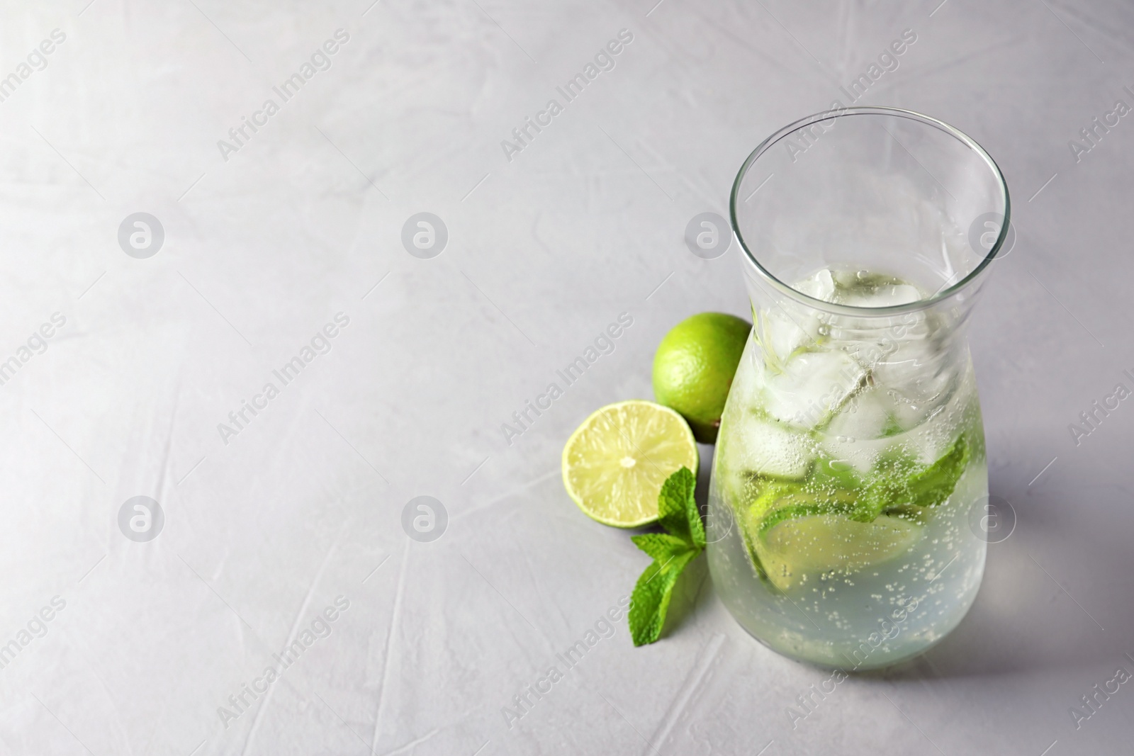 Photo of Natural lemonade with lime in jug on grey background