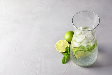 Photo of Natural lemonade with lime in jug on grey background