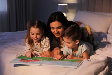 Photo of Mother reading bedtime story to her children at home