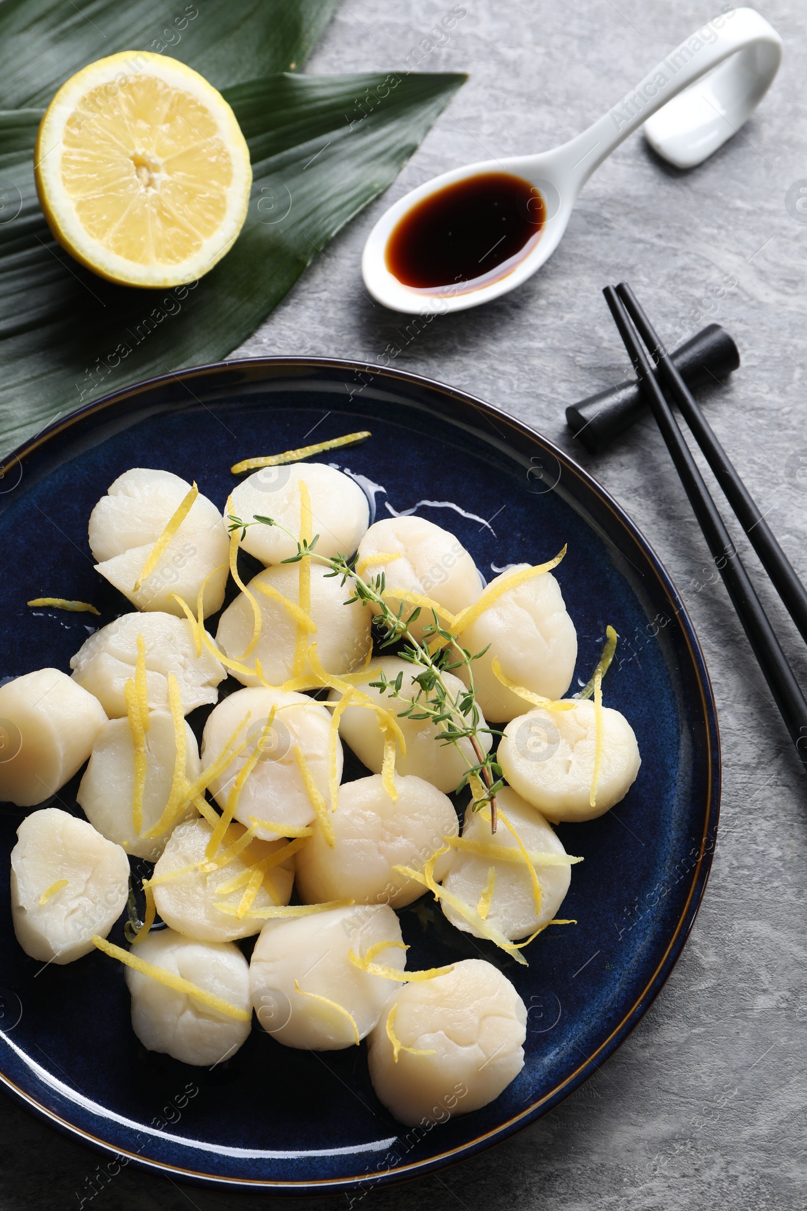 Photo of Raw scallops with thyme and lemon zest served on grey marble table, flat lay