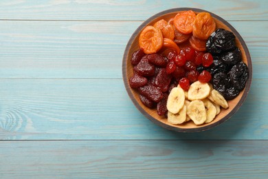 Photo of Mix of delicious dried fruits on light blue wooden table, top view. Space for text