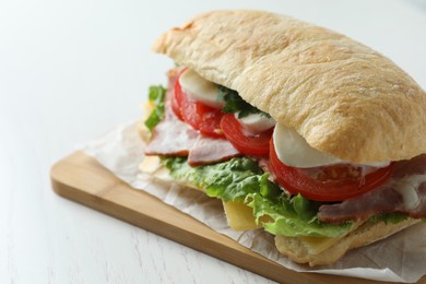 Photo of Delicious sandwich with fresh vegetables and mozzarella on white table, closeup