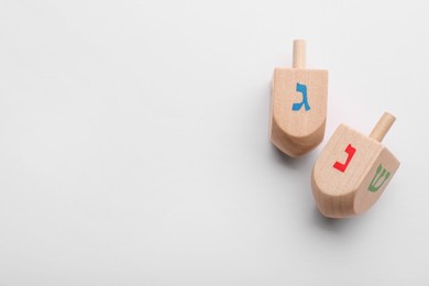 Photo of Wooden dreidels on white background, flat lay with space for text. Traditional Hanukkah game