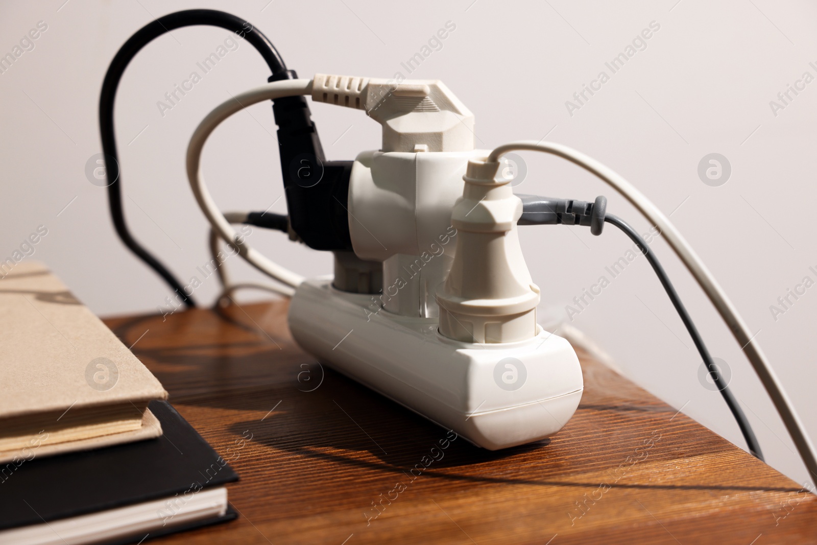 Photo of Smoking plug in power strip on wooden table, closeup. Electrical short circuit