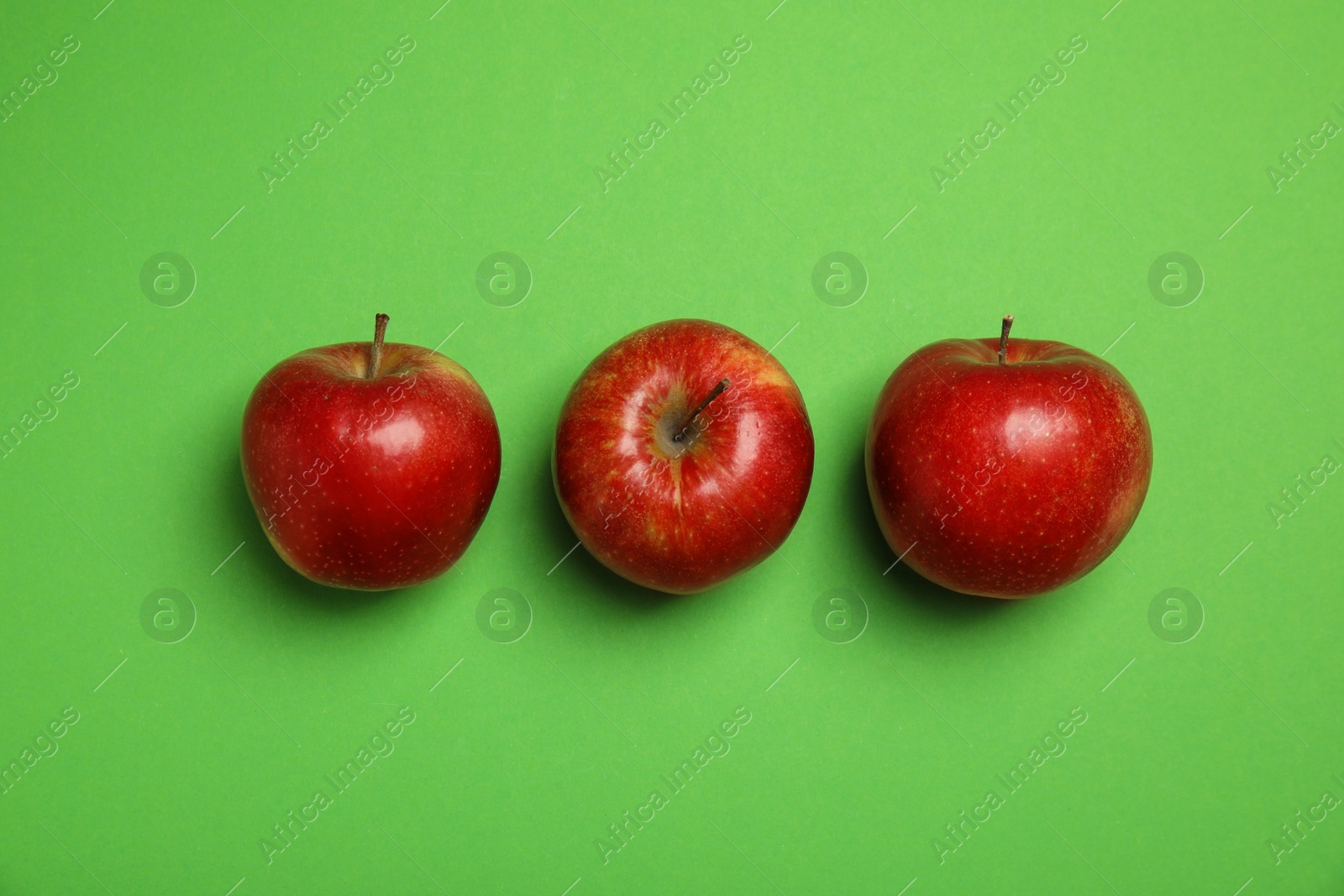 Photo of Flat lay composition with ripe juicy red apples on green background