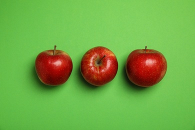 Flat lay composition with ripe juicy red apples on green background