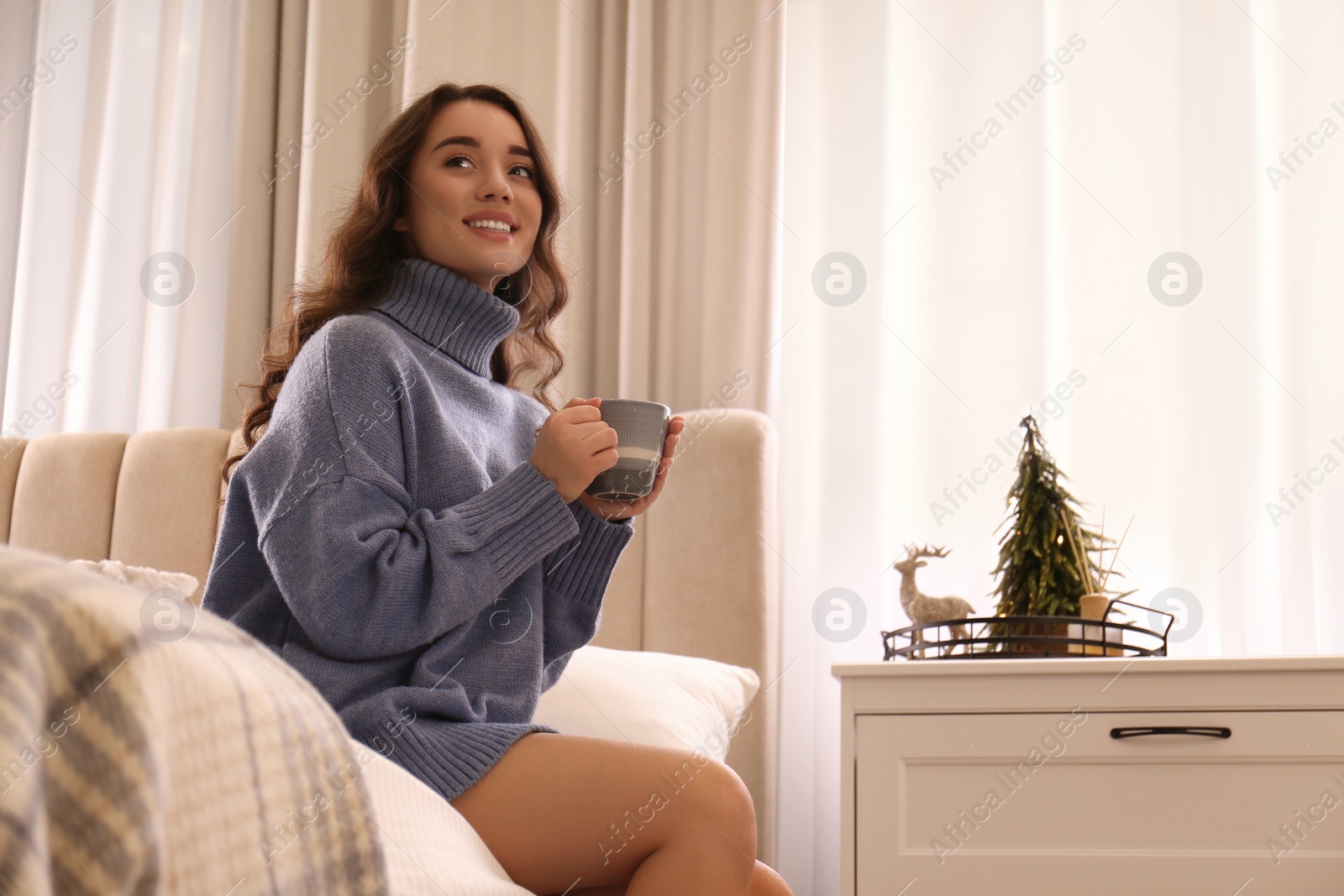 Photo of Woman with cup of hot drink resting at home. Winter atmosphere