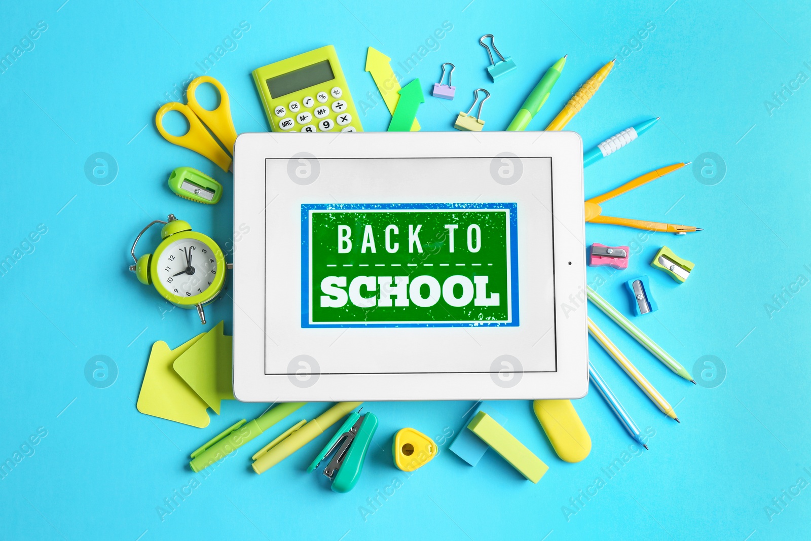 Photo of Tablet with phrase "BACK TO SCHOOL" and different stationery on blue background, flat lay