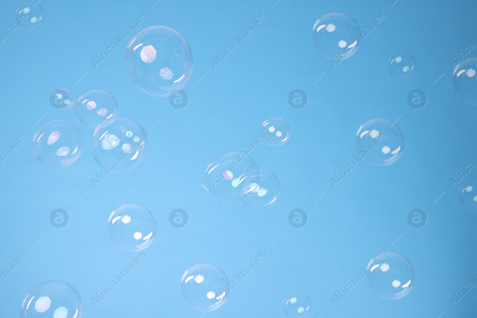 Photo of Many beautiful soap bubbles on light blue background. Space for text