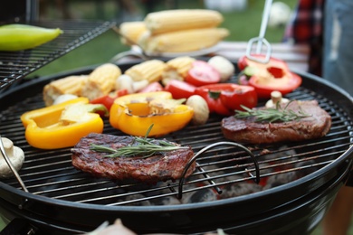 Photo of Barbecue grill with meat and vegetables outdoors, closeup