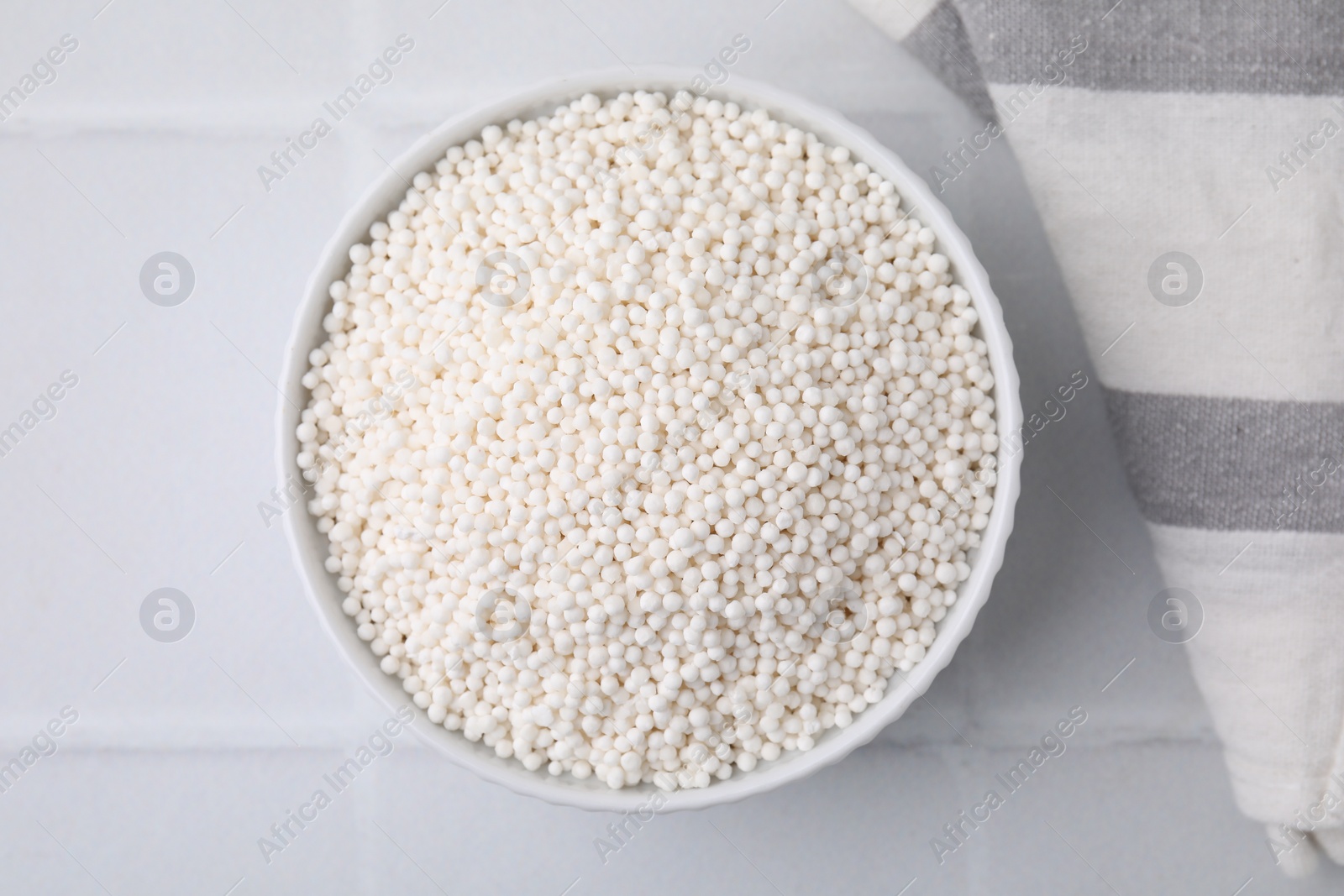 Photo of Tapioca pearls in bowl on white tiled table, top view