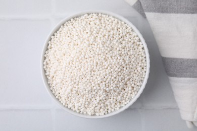 Photo of Tapioca pearls in bowl on white tiled table, top view