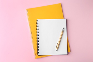 Photo of Notebooks and pen on pink background, top view