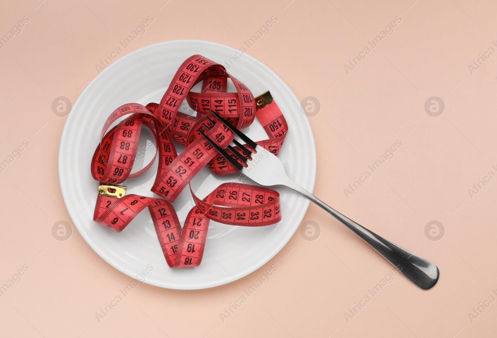 Photo of Plate, measuring tape and fork on beige background, top view. Diet concept