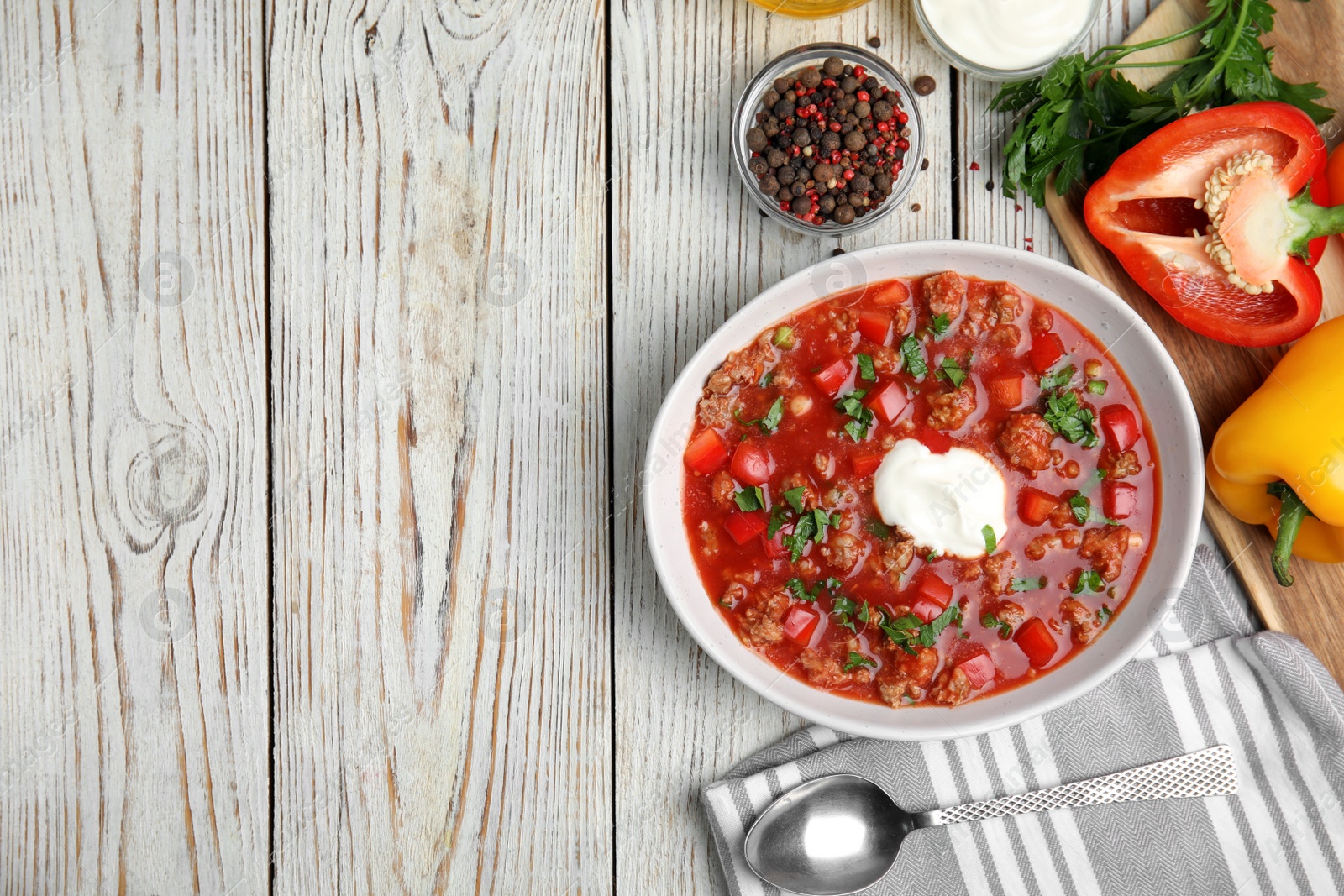 Photo of Bowl of delicious stuffed pepper soup on white wooden table, flat lay. Space for text