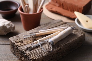 Photo of Set of different clay crafting tools on wooden table, closeup