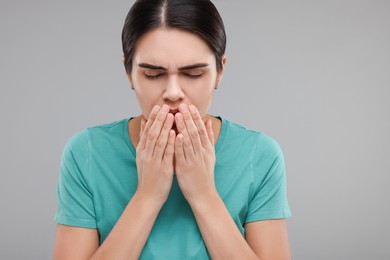 Woman coughing on grey background. Cold symptoms