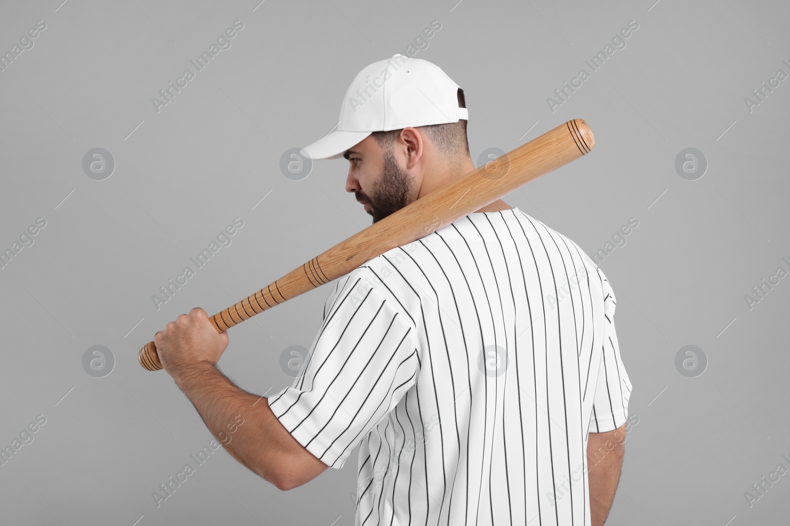 Photo of Man in stylish white baseball cap holding bat on light grey background